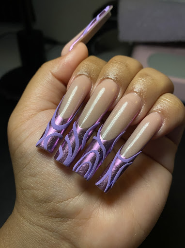 A woman's hand holding a purple and white manicure